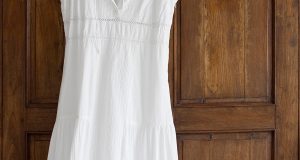 Biała sukienka na lato zawieszona na drzwiach