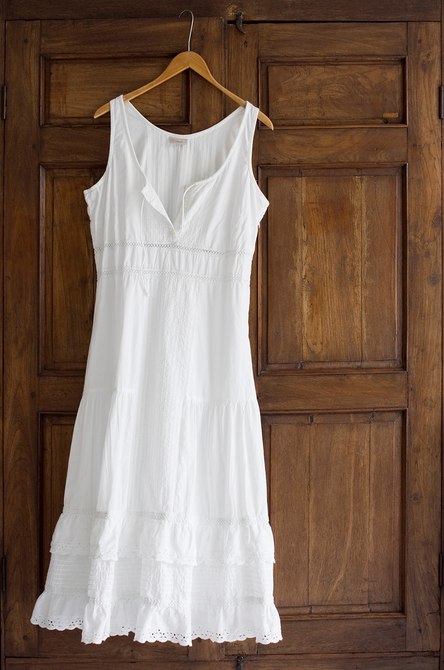 Biała sukienka na lato zawieszona na drzwiach