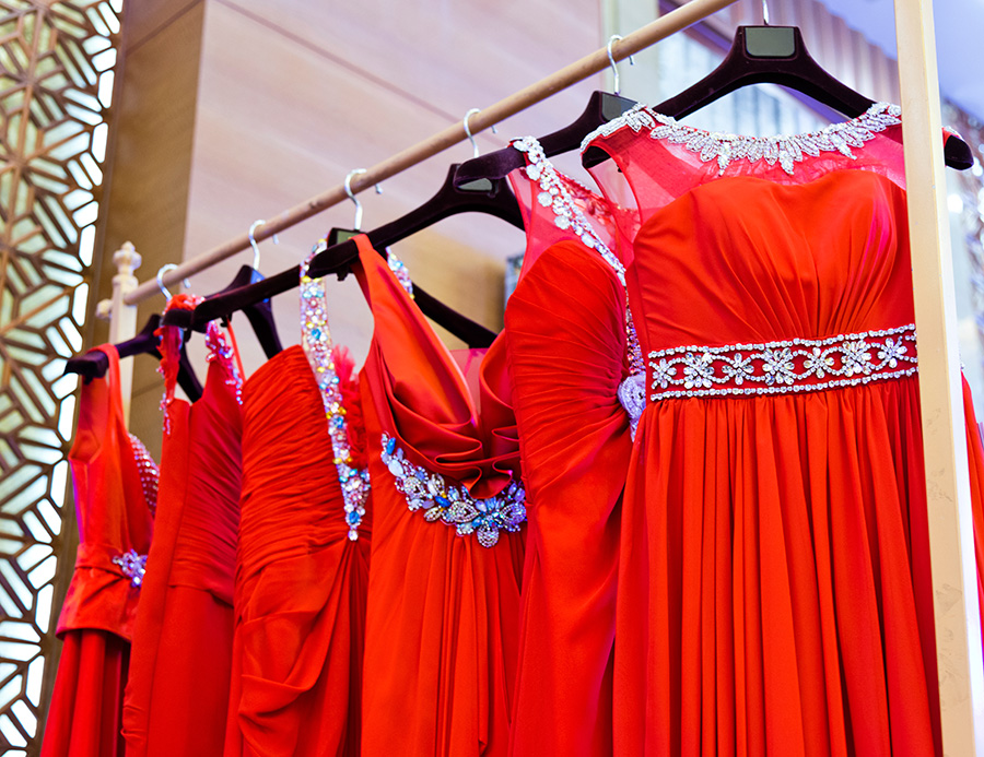 Eleganckie czerwone sukienki na wieszakach w sklepie
